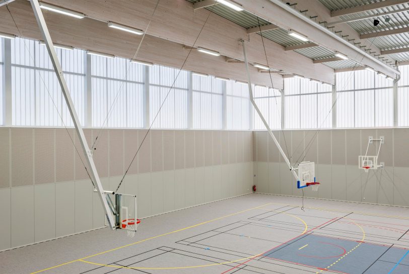 Minimalistic interior of Complexe Sportif featuring three basketball hoops in space with translucent wall panels from Kawall
