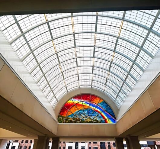 Translucent canopy with colorful stained glass design, enhancing daylighting in a commercial space, showcasing Kalwall's innovative architectural solutions.