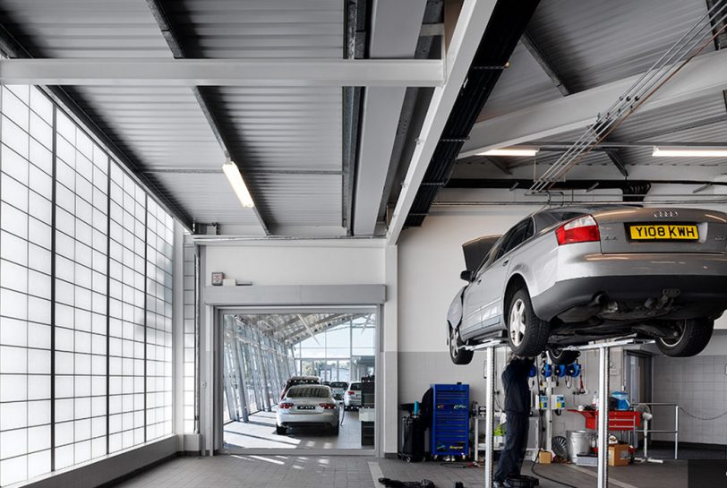Man working on Audi suspended in air, with natural daylighting provided from a Kalwall facade as the backdrop