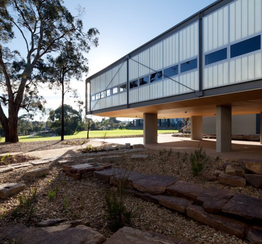 Exterior of building with a unitized curtain wall system on lifted columns surrounded by trees and rocks