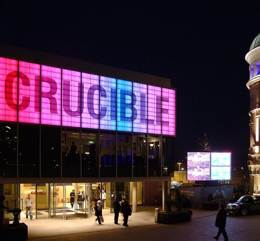 Crucible Theater building exterior with glass walls and sign with large lettering on Kalwall facade featuring backlighting