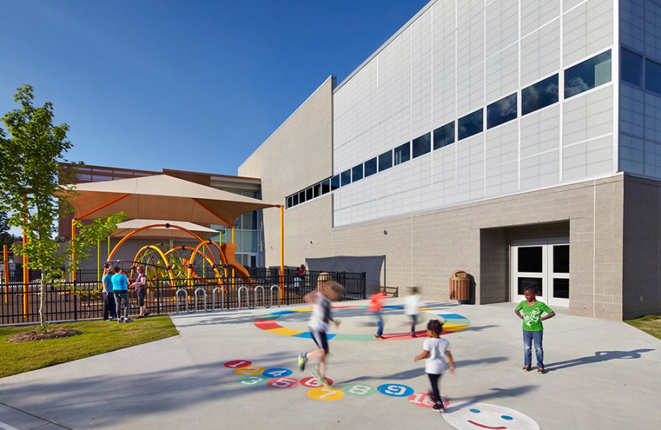 Children playing on colorful playground outside of Abbotts Creek Community Center featuring Kalwall unitized curtain wall