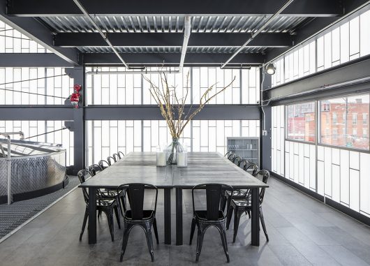 Kalwall facade application at Middle West Spirits showcased in office building with tables, chairs and industrial equipment