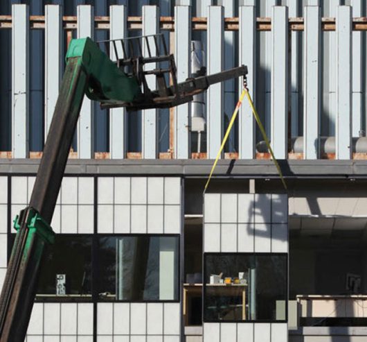 Exterior view of Kalwall translucent sandwich panels being installed on building with machinery