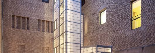 Exterior shot of building courtyard featuring light-colored brick building with Kalwall panel-clad tower.