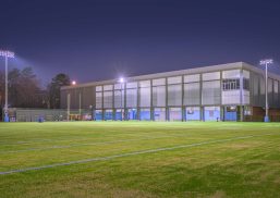 UNC football field at nighttime with building in the background featuring Kalwall facade.