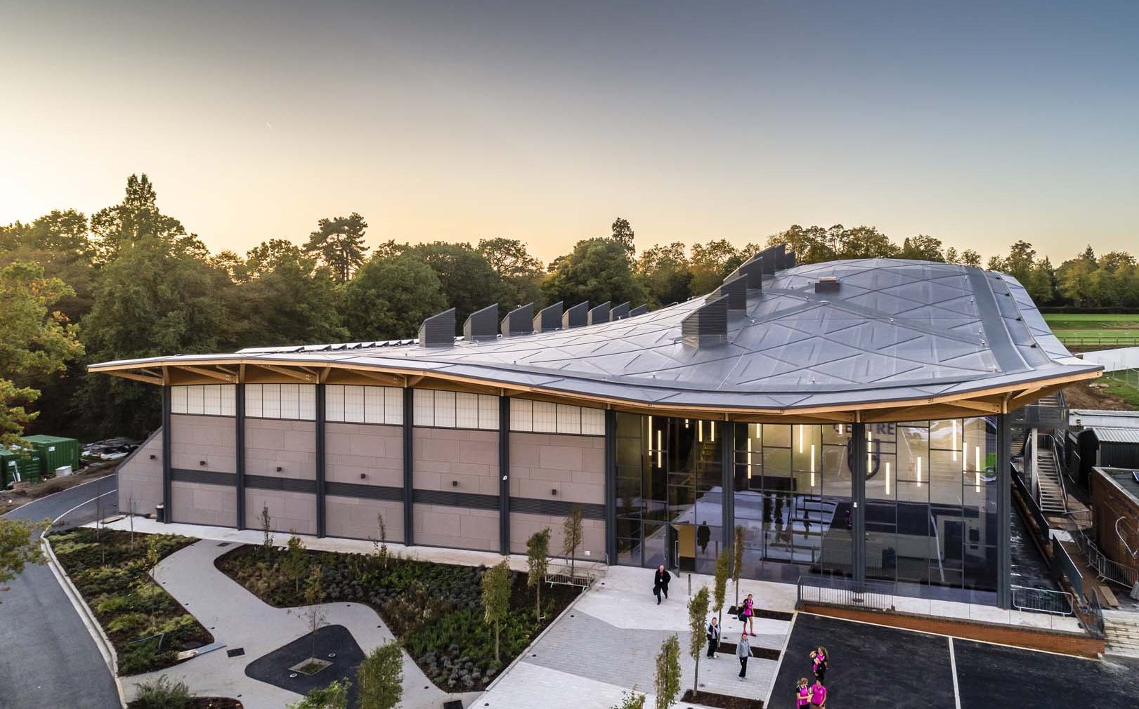 Exterior of Saint Georges College Sports Centre with curved roof and Kalwall facade on top portion of building wall.