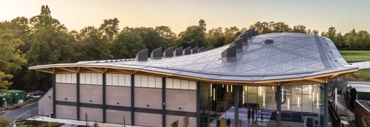 Exterior of Saint Georges College Sports Centre with curved roof and Kalwall facade on top portion of building wall.