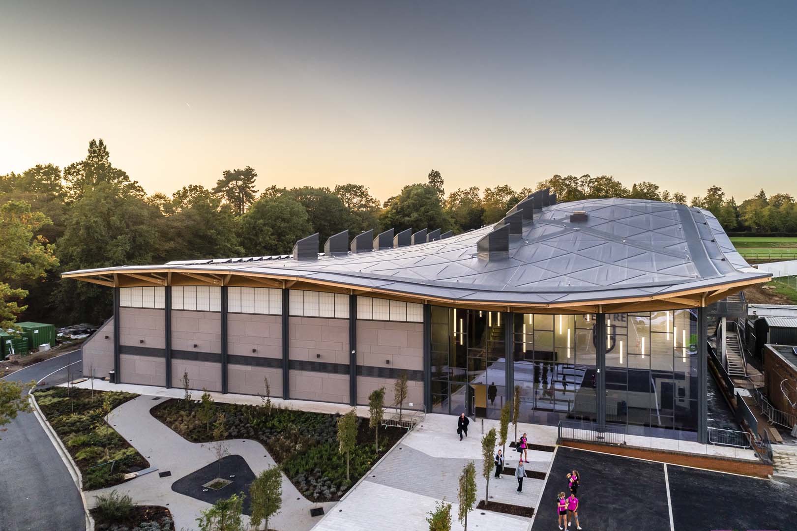 Exterior of Saint Georges College Sports Centre with curved roof and Kalwall facade on top portion of building wall.