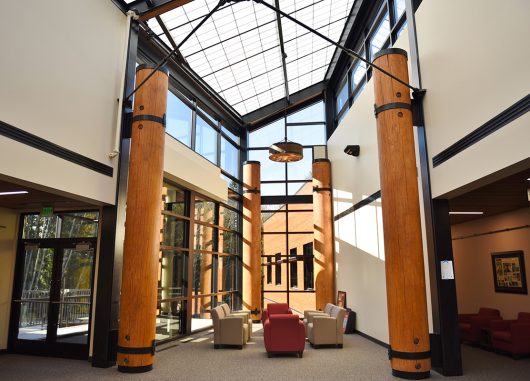 Building lobby with red and tan chairs, wooden columns and a Kalwall skylight creating perfectly diffuse daylight.