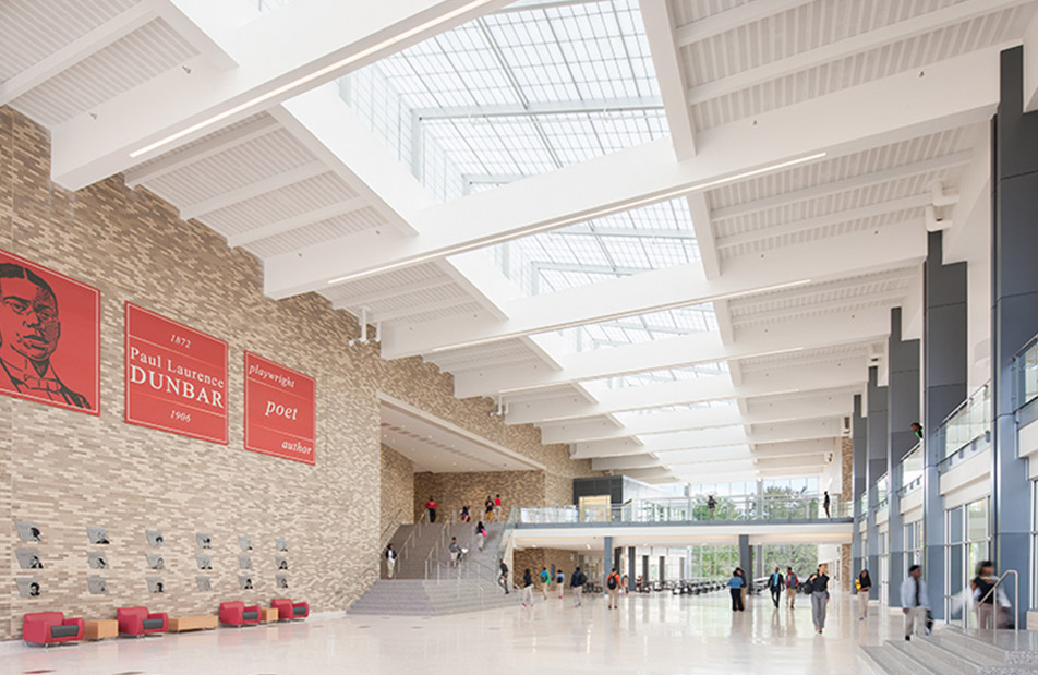 Students walking through Dunbar High School atrium featuring a clear span™ skyroof® from Kalwall