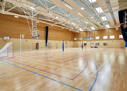 S-line skylights from Kalwall introduce daylighting to gymnasium with soccer nets and basketball hoops