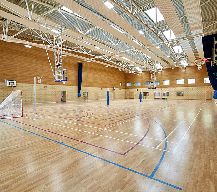 S-line skylights from Kalwall introduce daylighting to gymnasium with soccer nets and basketball hoops