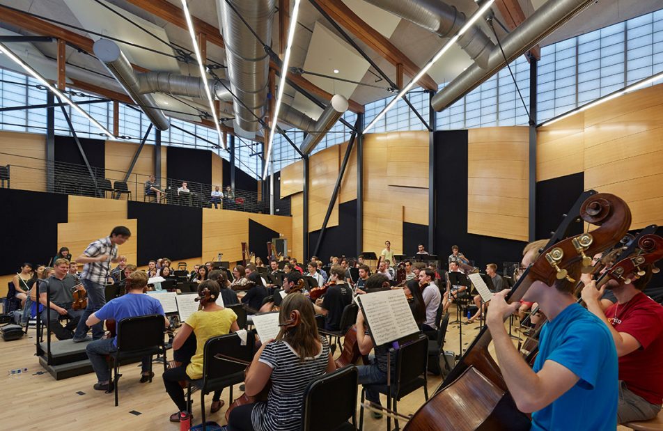 Interior of Aspen Music School shows students playing instruments in orchestra rehearsal with Kalwall facade on upper walls