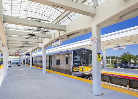 View of the Long Island Railroad Hicksville Station featuring a train and a Kalwall commercial canopy over standing area