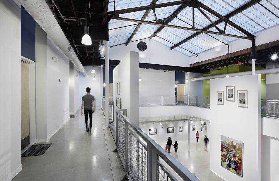 Elgin Artspace Lofts building featuring man walking on upper level while people walk below under Kalwall skyroof®