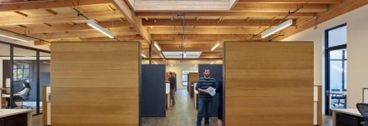 1060 Redwood office building interior with people standing among wooden walls, desks, and Kalwall translucent skylights above