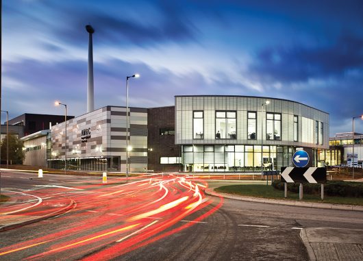 Building exterior at nighttime with blurred sky and blurred car lights featuring Kalwall unitized curtain wall panels