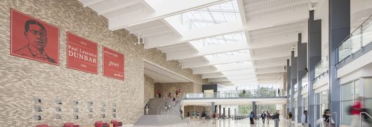 Dunbar High School interior with brick walls and students walking beneath Kalwall skylight system with white ceiling panels