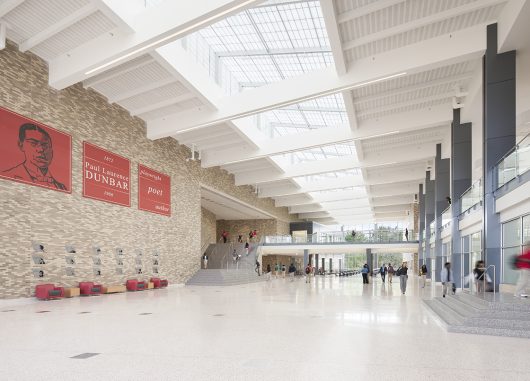 Dunbar High School interior with brick walls and students walking beneath Kalwall skylight system with white ceiling panels