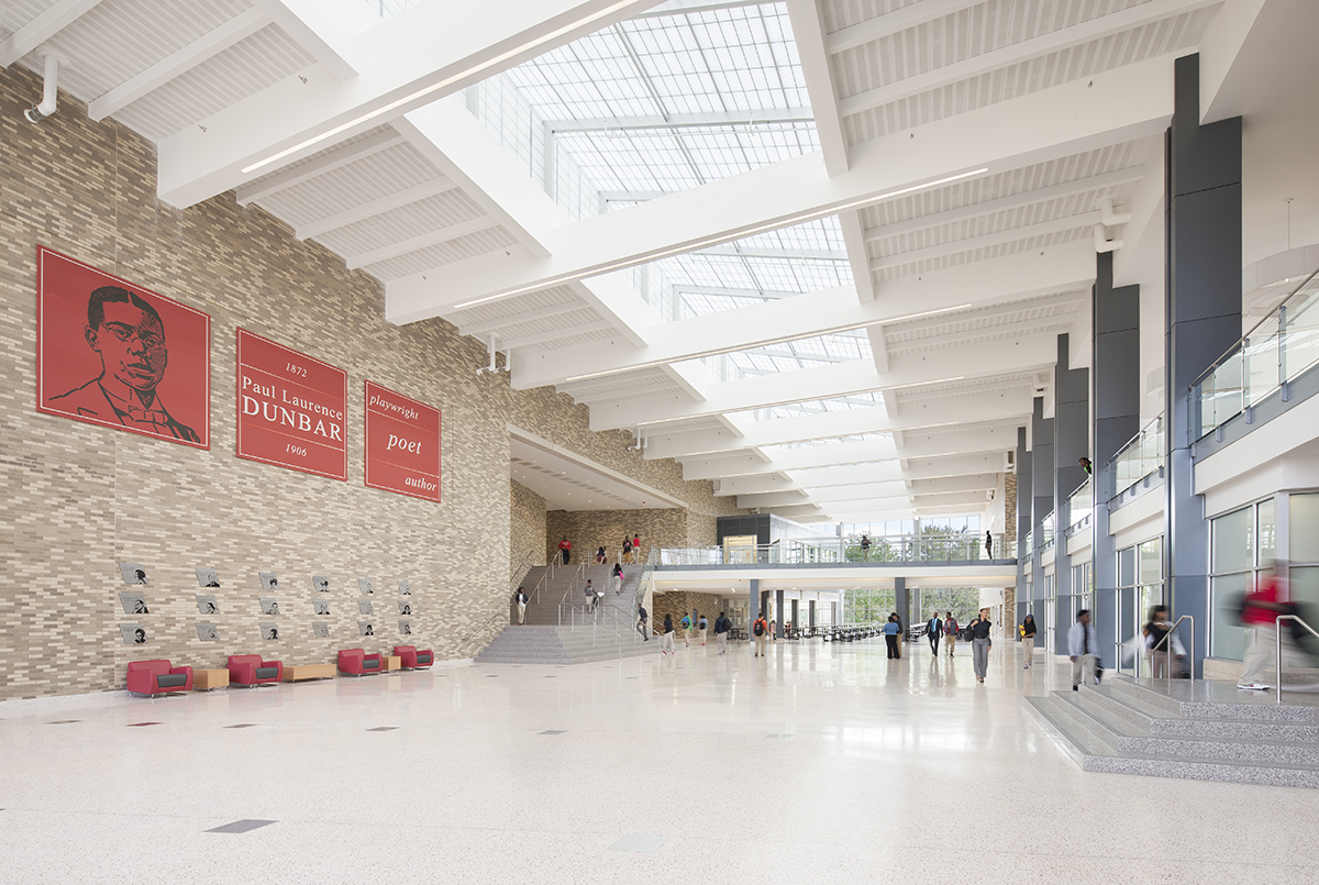 Dunbar High School interior with brick walls and students walking beneath Kalwall skylight system with white ceiling panels