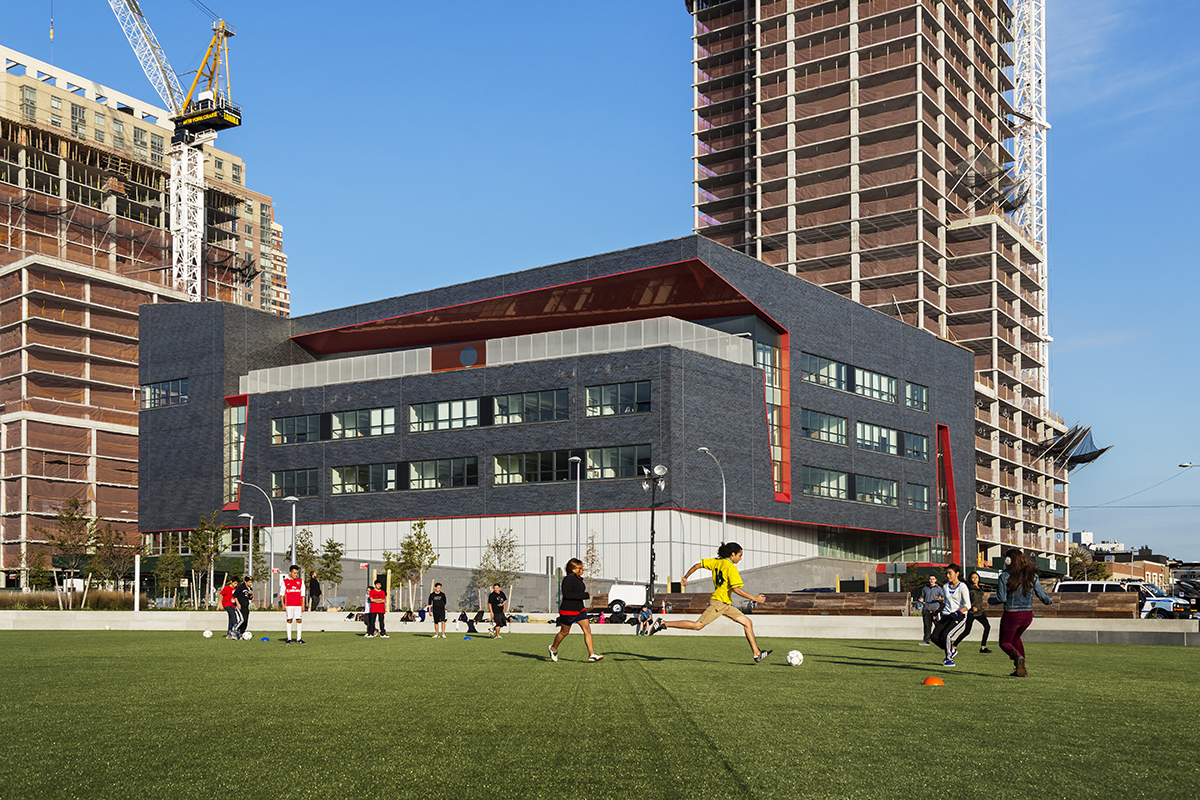 High school exterior with Kalwall curtain wall facade with kids playing soccer in foreground and two buildings in background