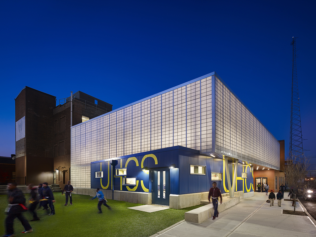 NJ charter school exterior at nighttime with dark blue sky and building of Kalwall curtain wall system with school letters