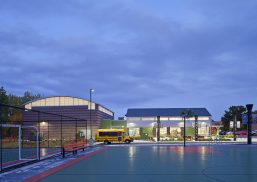 Boys & Girls Club exterior at nighttime featuring building with backlit Kalwall curtain wall system and school bus out front