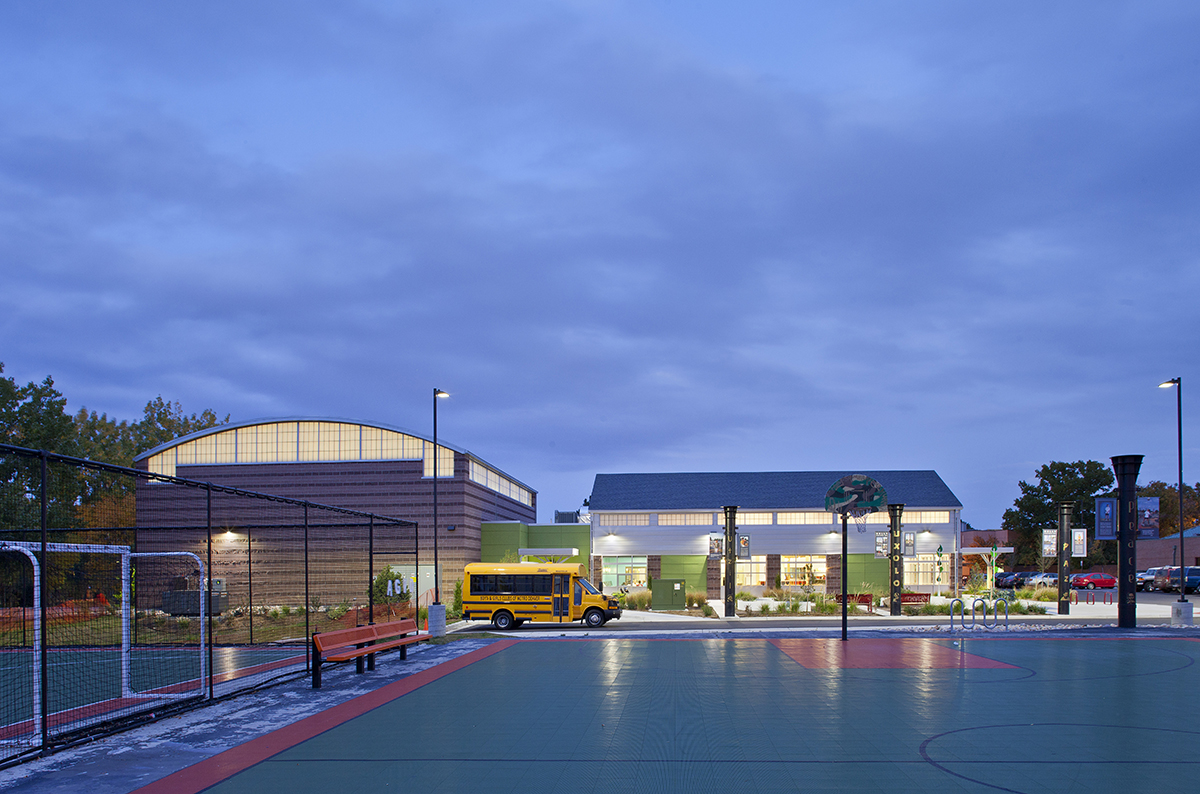 Boys & Girls Club exterior at nighttime featuring building with backlit Kalwall curtain wall system and school bus out front