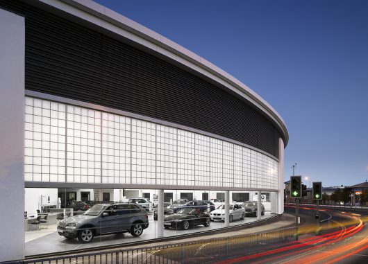 BMW exterior at dusk featuring blue sky, traffic lights and cars in a building with Kalwall translucent facade wall panels