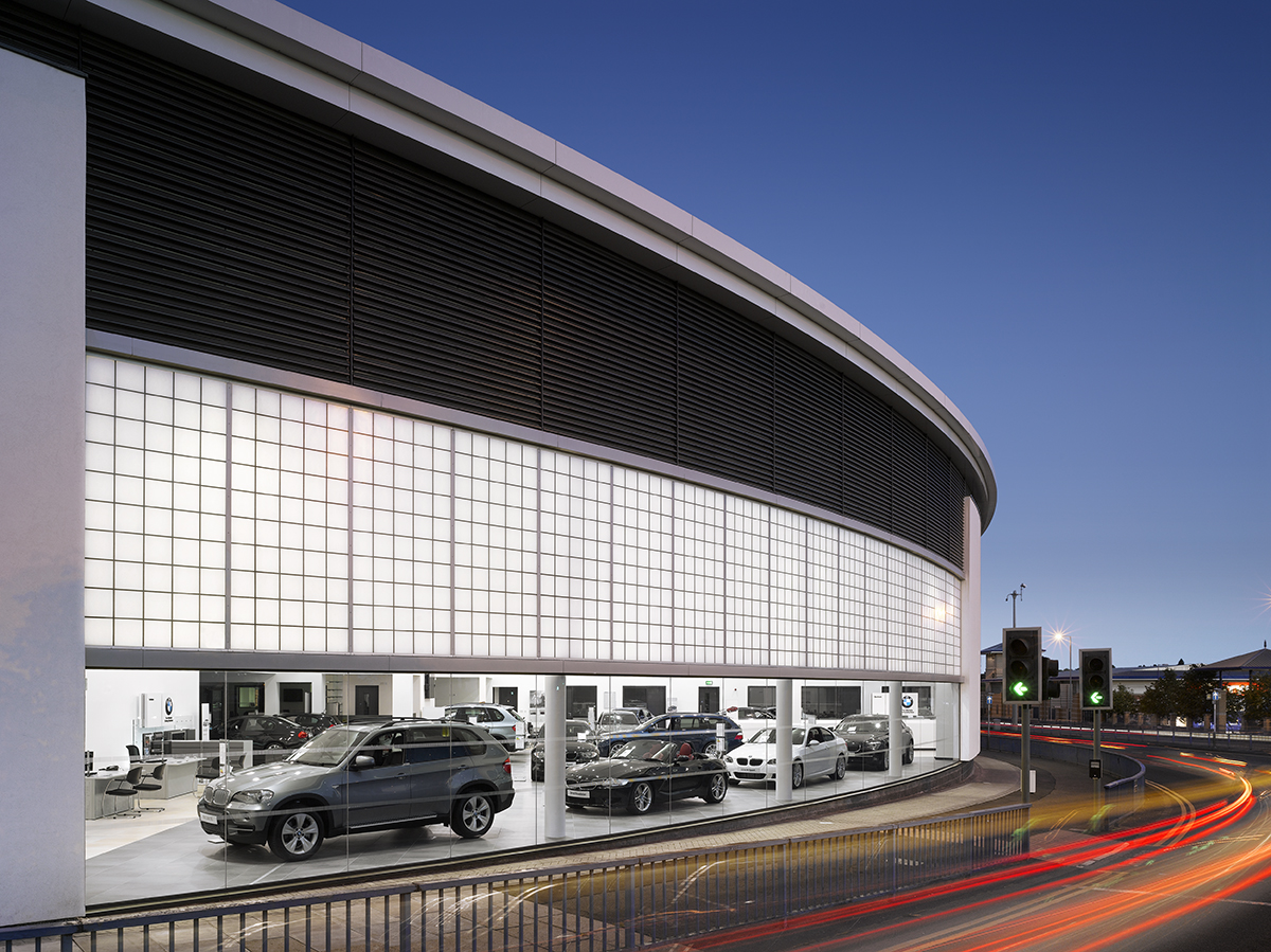 BMW exterior at dusk featuring blue sky, traffic lights and cars in a building with Kalwall translucent facade wall panels