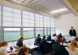 Classroom interior with students at desks and teacher standing at head of room with unitized curtain wall system by Kalwall