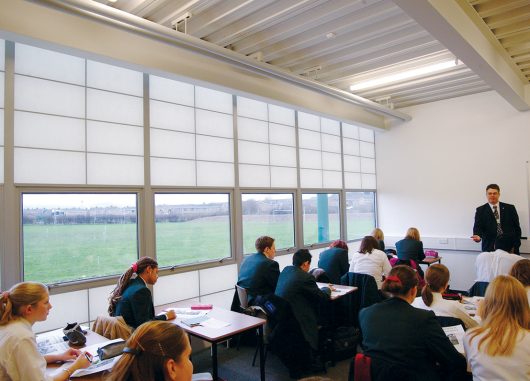 Classroom interior with students at desks and teacher standing at head of room with unitized curtain wall system by Kalwall