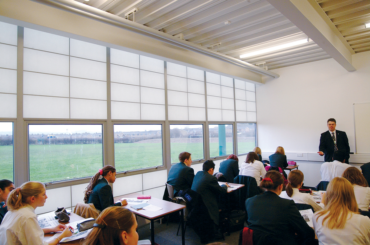 Classroom interior with students at desks and teacher standing at head of room with unitized curtain wall system by Kalwall