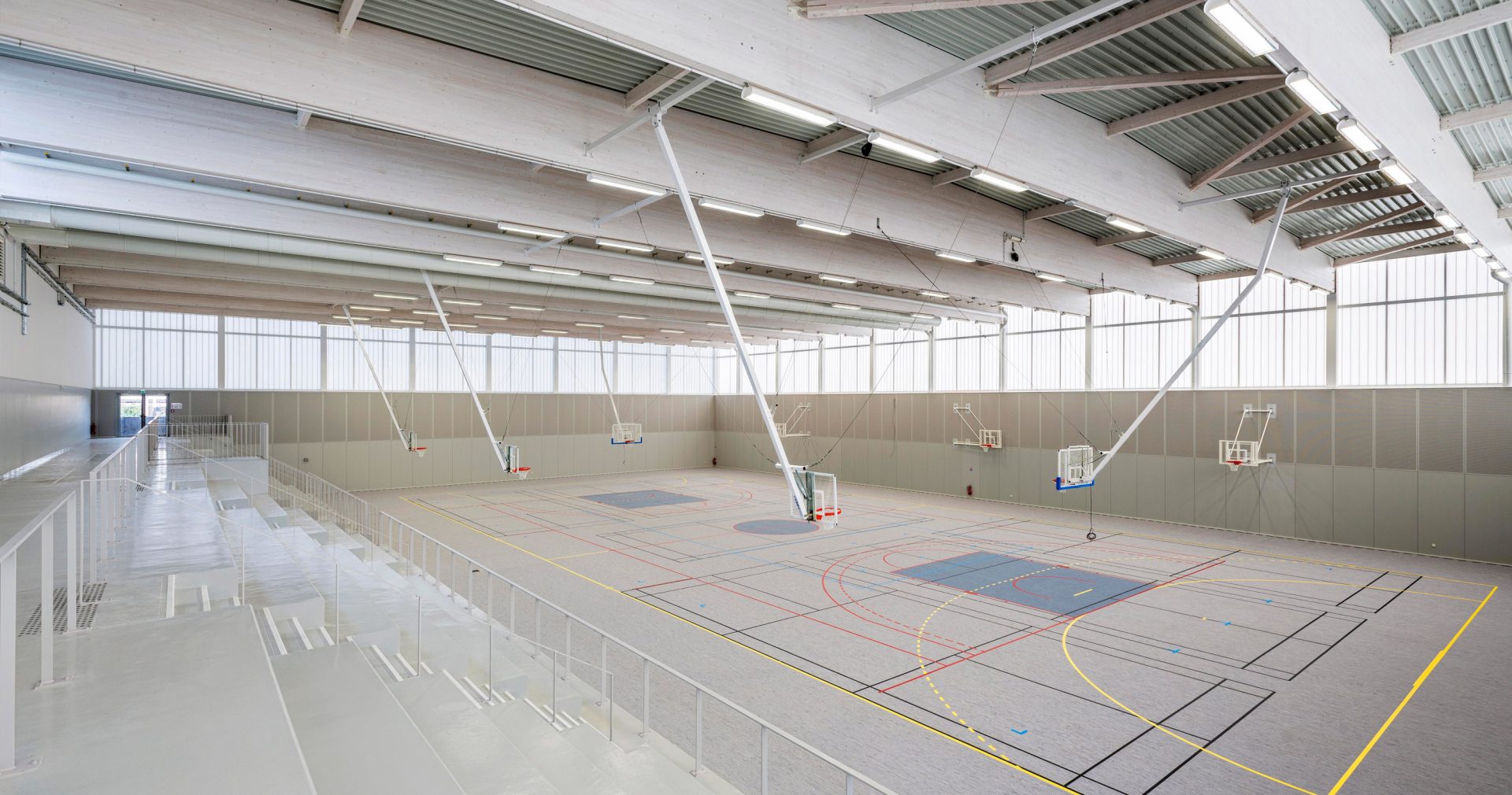 Minimalistic interior of Complexe Sportif featuring three basketball hoops in space with translucent wall panels from Kawall