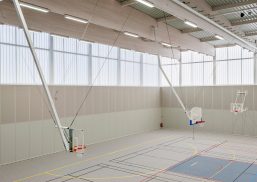 Minimalistic interior of Complexe Sportif featuring three basketball hoops in space with translucent wall panels from Kawall