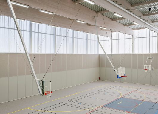 Minimalistic interior of Complexe Sportif featuring three basketball hoops in space with translucent wall panels from Kawall