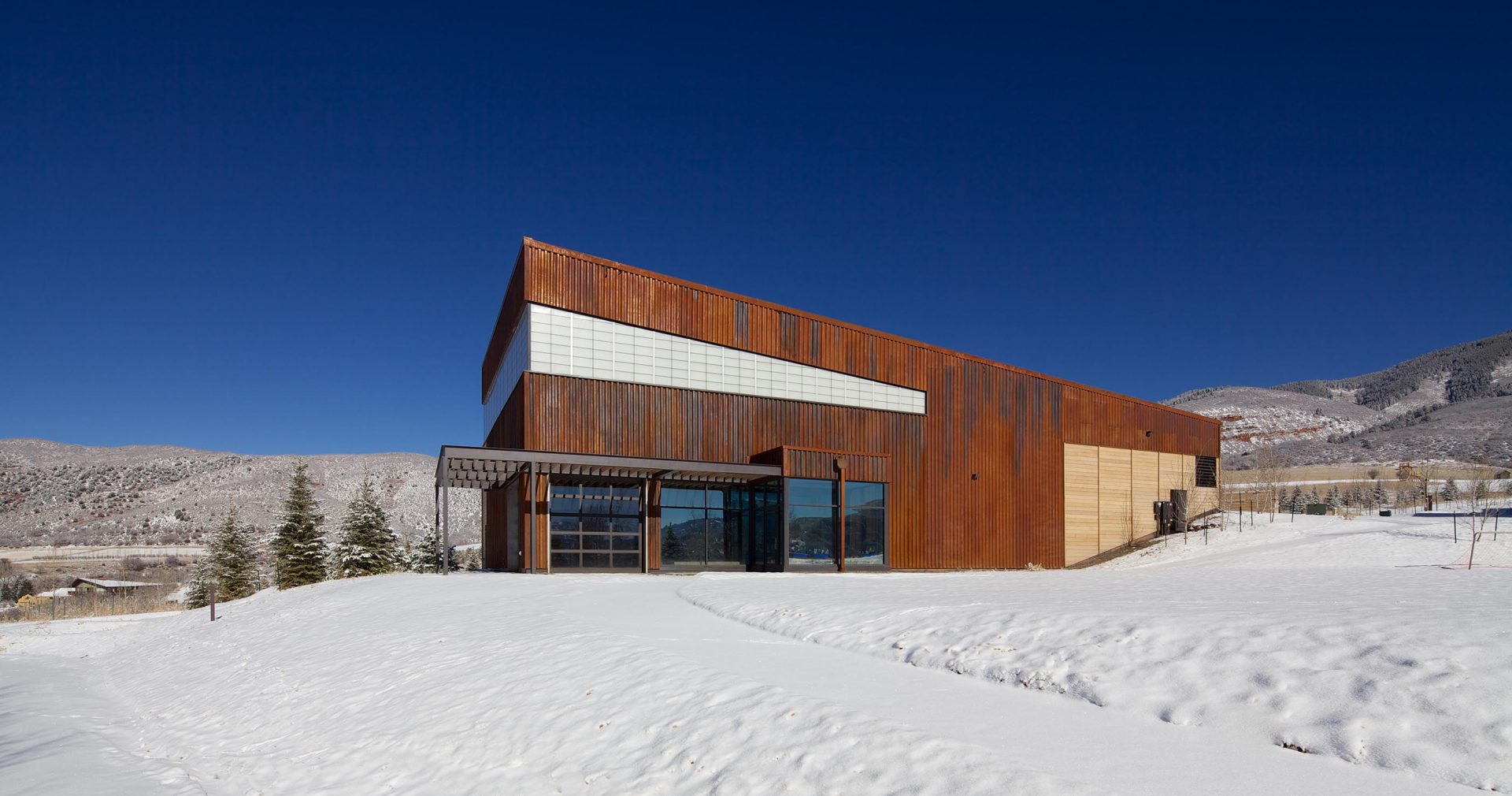 Aspen Community School exterior in winter with snow surrounding wooden building featuring Kalwall translucent window wall