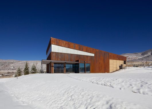 Aspen Community School exterior in winter with snow surrounding wooden building featuring Kalwall translucent window wall