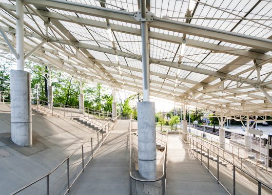 Rapid transit station in Ohio featuring sloped Kalwall translucent canopy over cinderblock columns and greenery in background