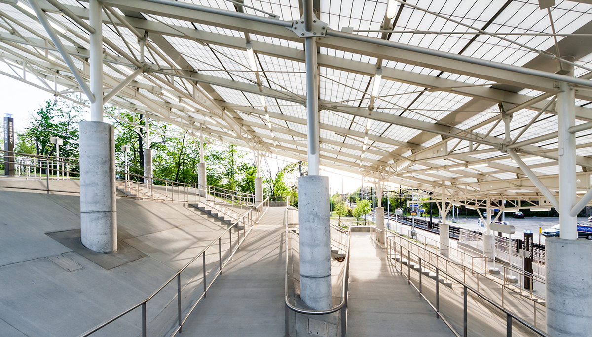 Rapid transit station in Ohio featuring sloped Kalwall translucent canopy over cinderblock columns and greenery in background