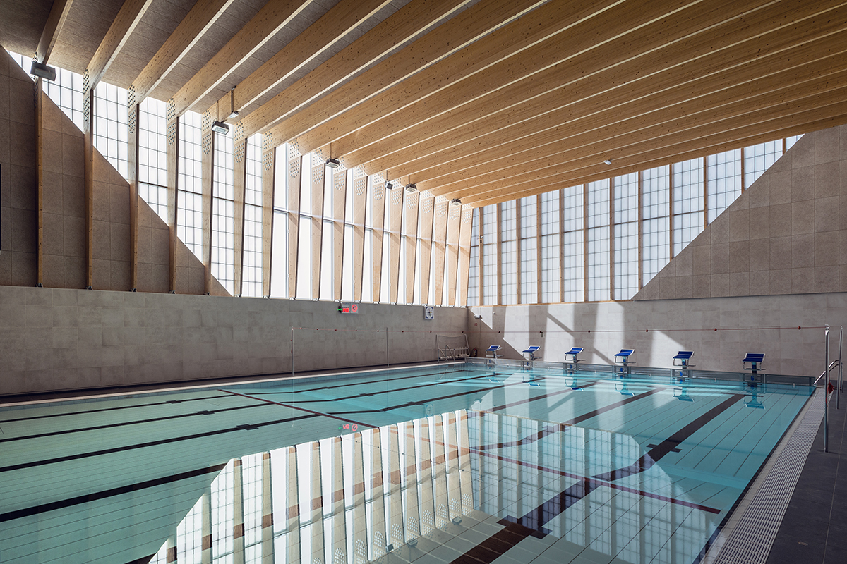 British School of Brussels pool enclosure featuring wooden ceiling beams and Kalwall translucent curtain wall system