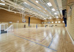 Cheltenham Ladies College gymnasium interior featuring wooden floors, brick and wooden walls, and skylights