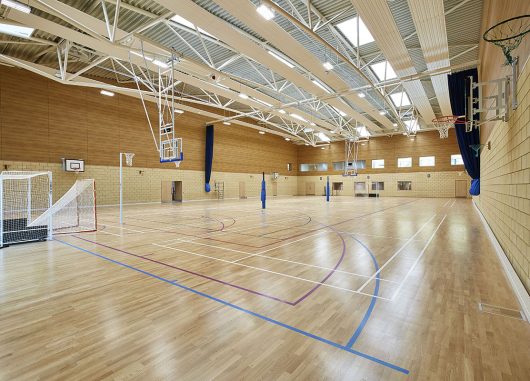 Cheltenham Ladies College gymnasium interior featuring wooden floors, brick and wooden walls, and skylights