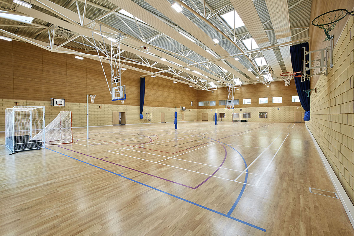 Cheltenham Ladies College gymnasium interior featuring wooden floors, brick and wooden walls, and skylights