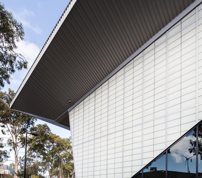 Building exterior featuring Kalwall facade with translucent sandwich panels surrounded by trees and blue sky