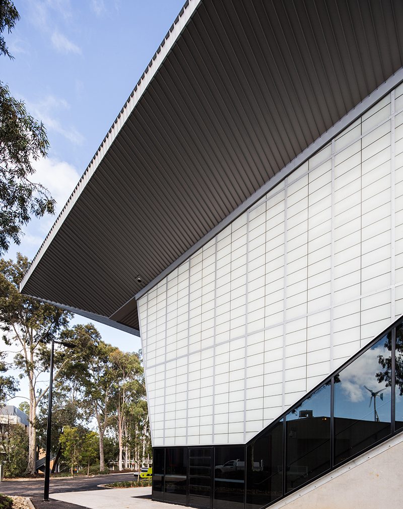 Building exterior featuring Kalwall facade with translucent sandwich panels surrounded by trees and blue sky