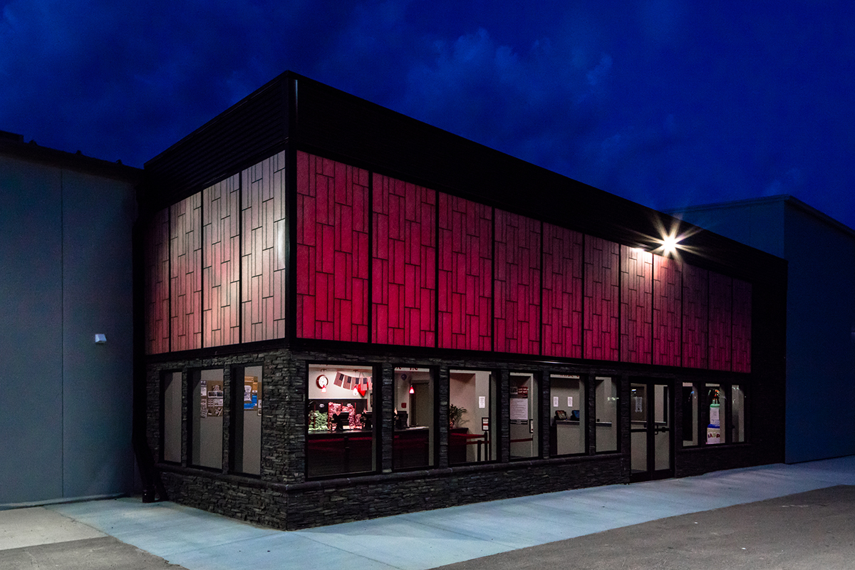 Nighttime exterior of gray brick building with Kalwall unitized curtain wall system featuring pink backlighting