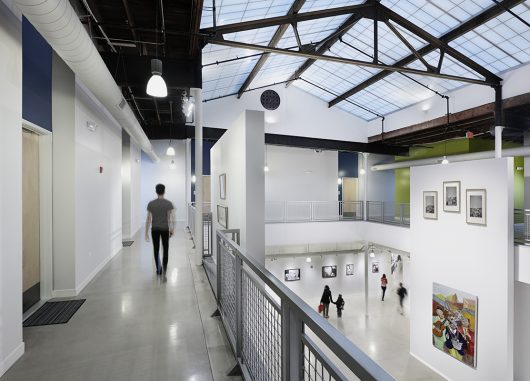 Elgin Artspace Lofts building featuring man walking on upper level while people walk below under Kalwall skyroof®