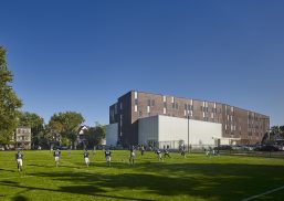 Football players on field at KIPP Newark Collegiate Academy with brick building in background featuring Kalwall wall system